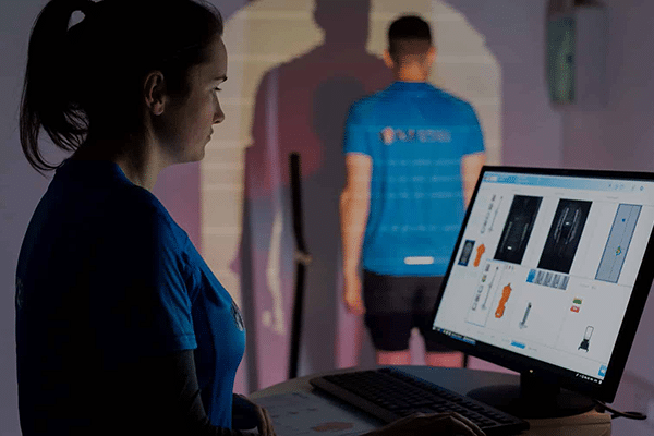 Medical professional reviewing full body scan images on a computer with another healthcare worker in the background. | FCE Scan